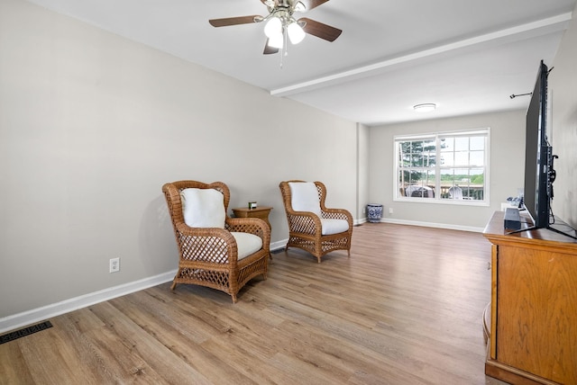 living area with baseboards, a ceiling fan, light wood-style flooring, and visible vents