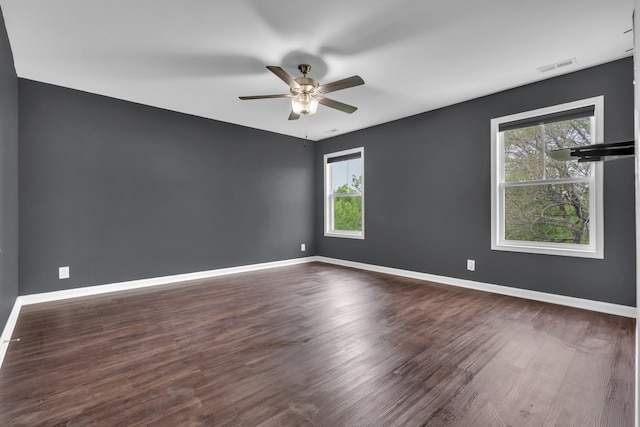 spare room with wood finished floors, plenty of natural light, a ceiling fan, and visible vents