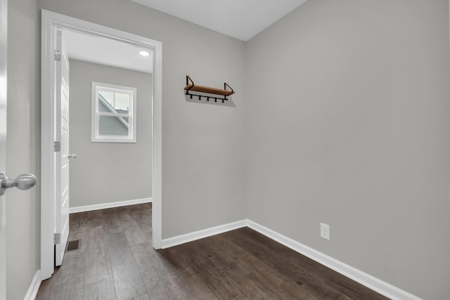 unfurnished room with baseboards and dark wood-style floors