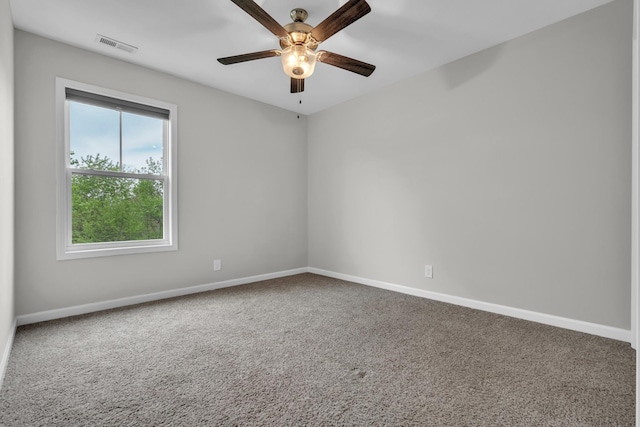carpeted empty room featuring visible vents, a ceiling fan, and baseboards