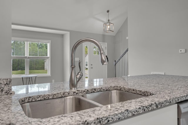 details featuring light stone countertops, pendant lighting, stainless steel dishwasher, and a sink