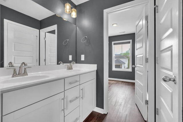 bathroom with wood finished floors, baseboards, a sink, and double vanity