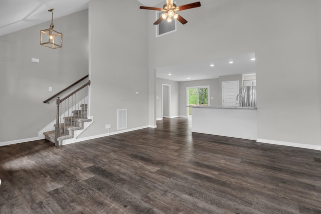 unfurnished living room featuring stairway, ceiling fan, a towering ceiling, dark wood-type flooring, and visible vents
