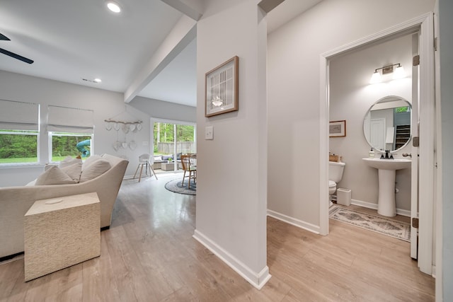 corridor with baseboards, recessed lighting, light wood finished floors, and a sink