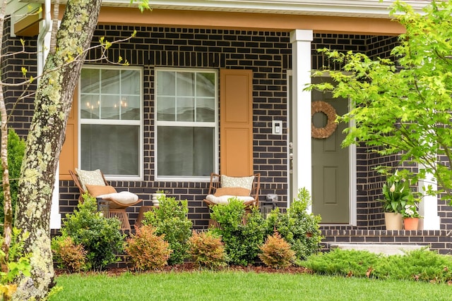 doorway to property with covered porch and brick siding