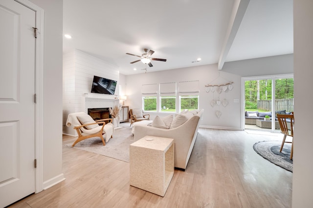 living room featuring light wood finished floors, a tile fireplace, and a wealth of natural light