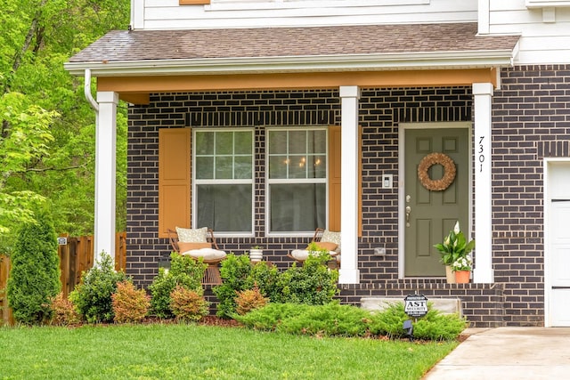 doorway to property with covered porch, brick siding, fence, and a shingled roof