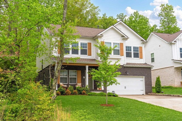 view of front of home featuring a front lawn, a garage, a shingled roof, driveway, and brick siding