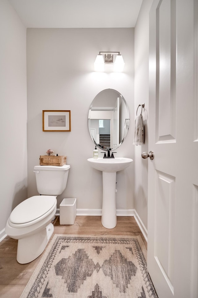bathroom with wood finished floors, toilet, and baseboards