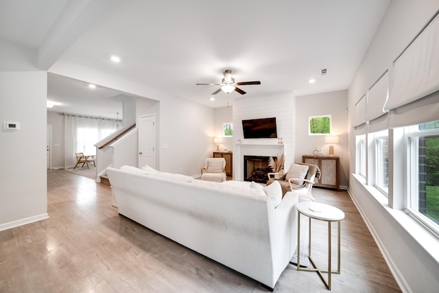 living room with light wood-type flooring, recessed lighting, ceiling fan, and a fireplace