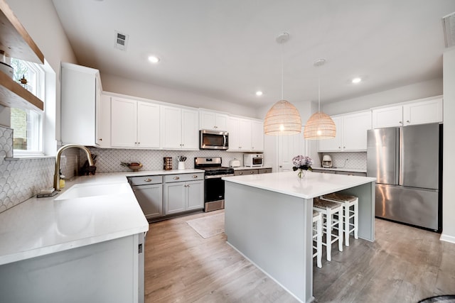 kitchen with a sink, stainless steel appliances, a kitchen bar, a center island, and backsplash