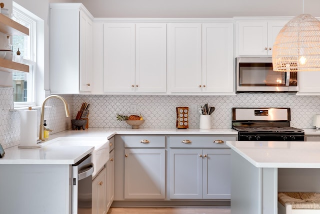 kitchen featuring stainless steel appliances, a sink, light countertops, and decorative backsplash