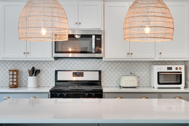 kitchen featuring white cabinets, appliances with stainless steel finishes, light countertops, a toaster, and backsplash