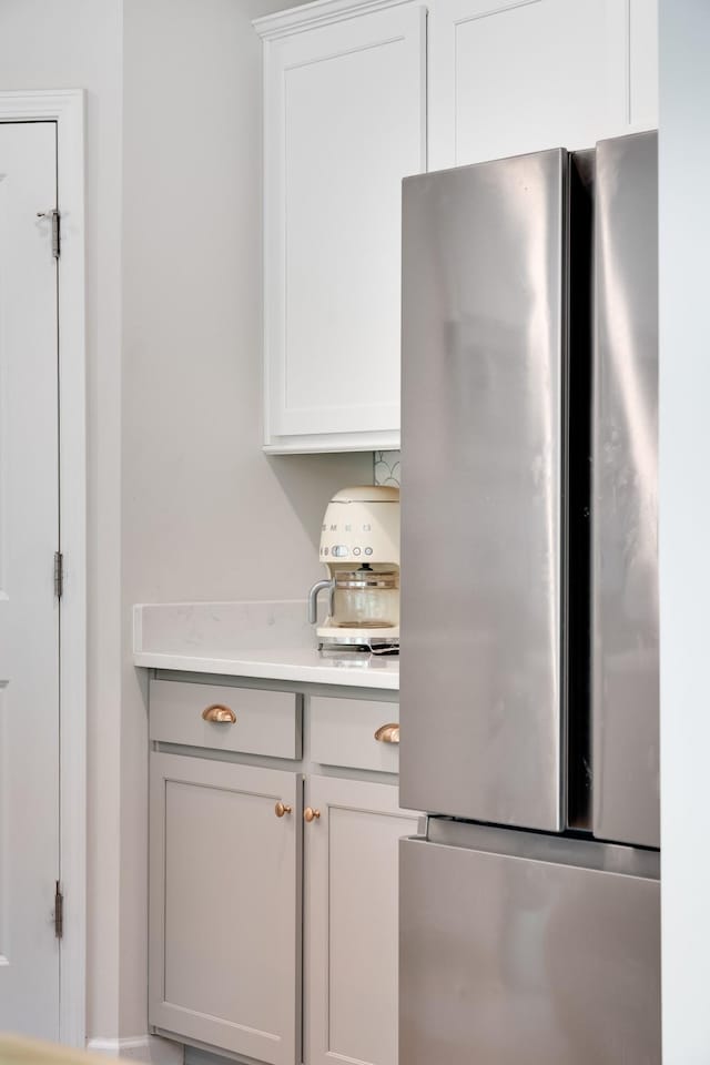 kitchen featuring light countertops, white cabinets, and freestanding refrigerator