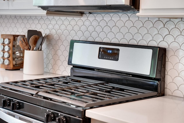 details featuring light countertops, stainless steel range with gas stovetop, under cabinet range hood, and tasteful backsplash