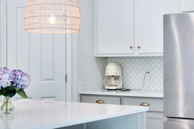 room details with white cabinetry, light countertops, freestanding refrigerator, and tasteful backsplash