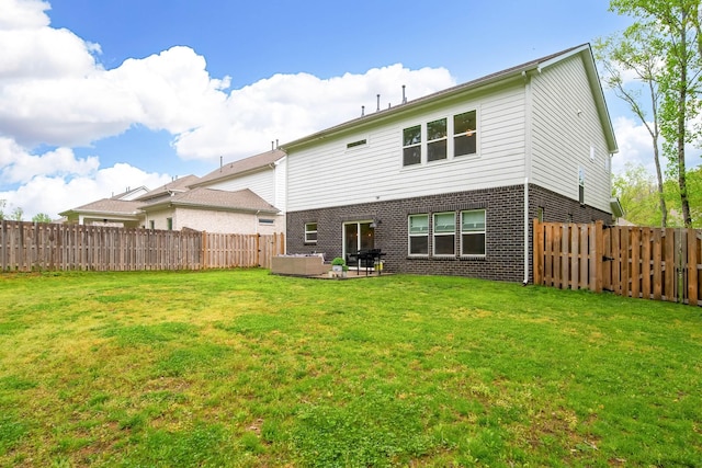 rear view of house featuring a lawn, a patio, a fenced backyard, and brick siding