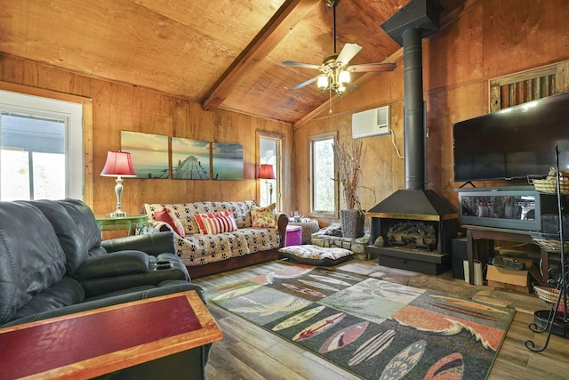 living area featuring lofted ceiling with beams, wooden ceiling, a wealth of natural light, and a wood stove
