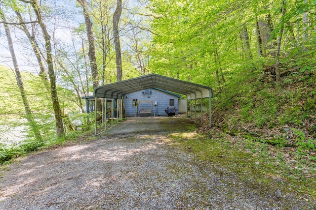 exterior space with a carport, driveway, and a forest view