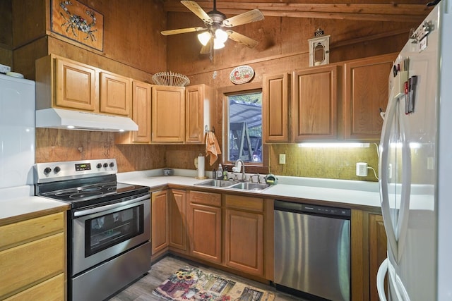 kitchen with under cabinet range hood, stainless steel appliances, light countertops, and a sink