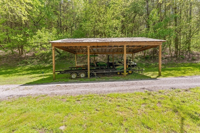 view of home's community featuring a view of trees, a lawn, and a carport