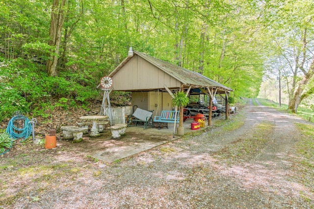 view of outbuilding featuring dirt driveway and a view of trees