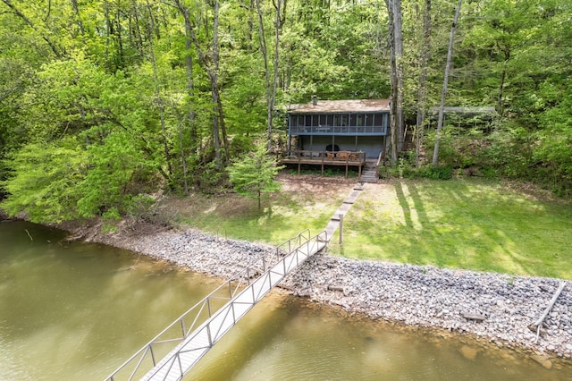 dock area featuring a lawn, a view of trees, and a deck with water view