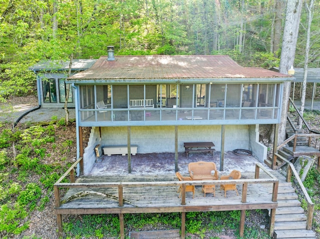 back of house featuring a sunroom, a deck, stairs, and metal roof