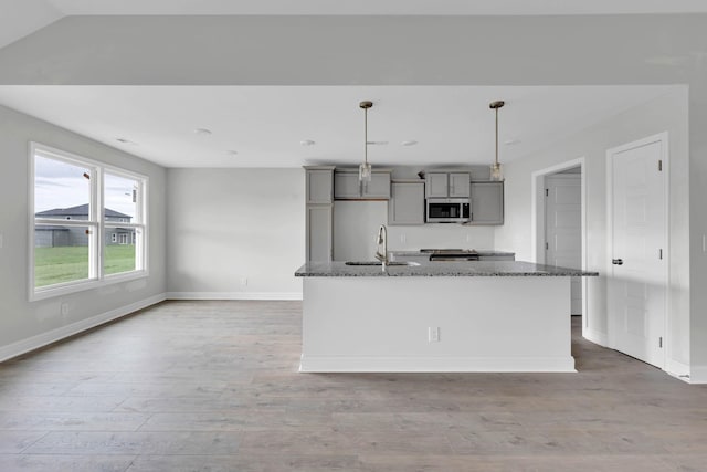 358 Galway Dr, Clarksville, TN 37042 - kitchen with gray cabinets, appliances with stainless steel finishes, dark stone counters, wood finished floors, and a kitchen island with sink