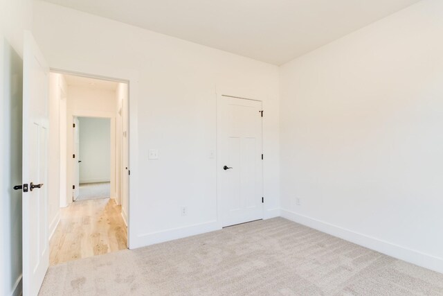 unfurnished bedroom featuring light colored carpet, baseboards, and a closet
