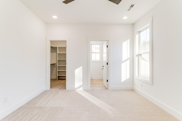 unfurnished bedroom featuring a walk in closet, carpet, baseboards, visible vents, and recessed lighting