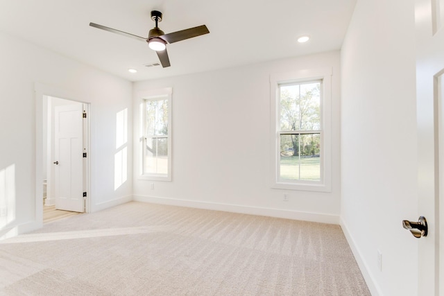 spare room with light colored carpet, a wealth of natural light, and baseboards