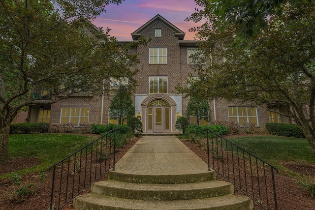 view of property featuring brick siding and a front yard