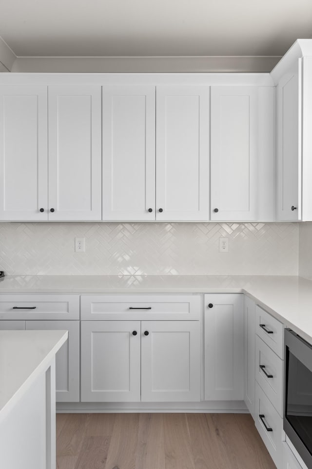 430 Mercomatic Dr, Nashville, TN 37209 - kitchen featuring tasteful backsplash, built in microwave, light countertops, light wood-style flooring, and white cabinetry