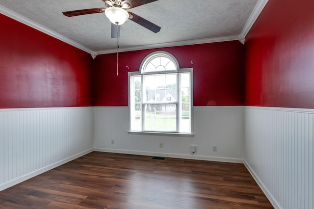 empty room with wainscoting, wood finished floors, and a wealth of natural light