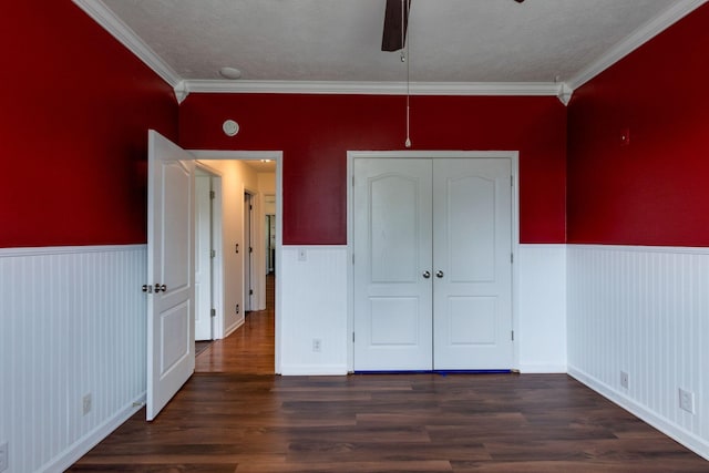 unfurnished bedroom featuring ornamental molding, dark wood-type flooring, and a wainscoted wall