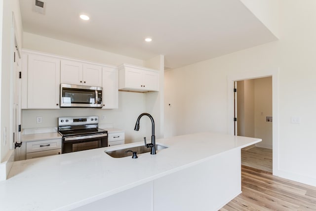 kitchen with a sink, light wood-style floors, stainless steel appliances, white cabinets, and visible vents