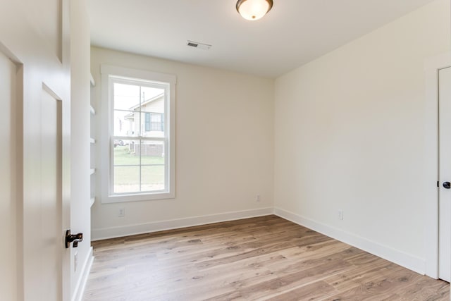 empty room with light wood finished floors, plenty of natural light, baseboards, and visible vents
