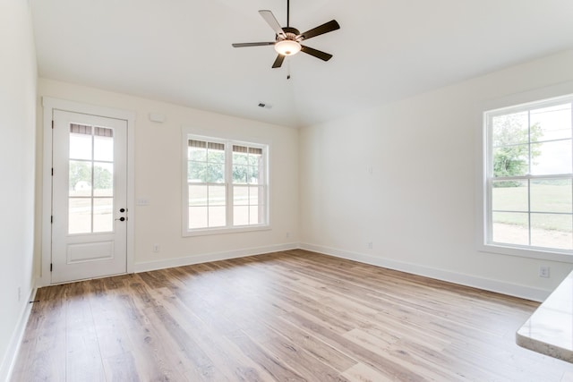interior space featuring lofted ceiling, visible vents, light wood-style floors, baseboards, and ceiling fan