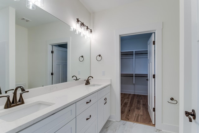 bathroom with a spacious closet, a sink, visible vents, and double vanity