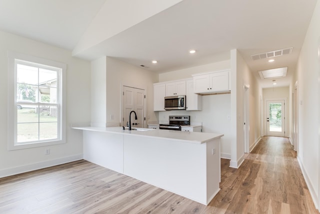 kitchen with stainless steel appliances, light countertops, visible vents, a sink, and light wood-type flooring