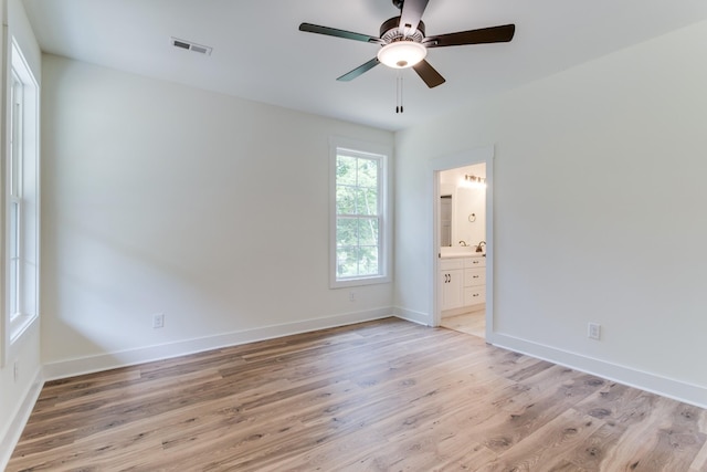 unfurnished bedroom featuring visible vents, light wood-type flooring, ensuite bath, baseboards, and ceiling fan