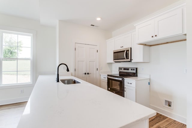 kitchen with a sink, light wood-type flooring, stainless steel appliances, baseboards, and visible vents