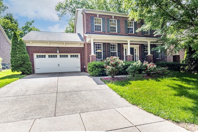 view of front of house with brick siding, driveway, a garage, a front yard, and a porch