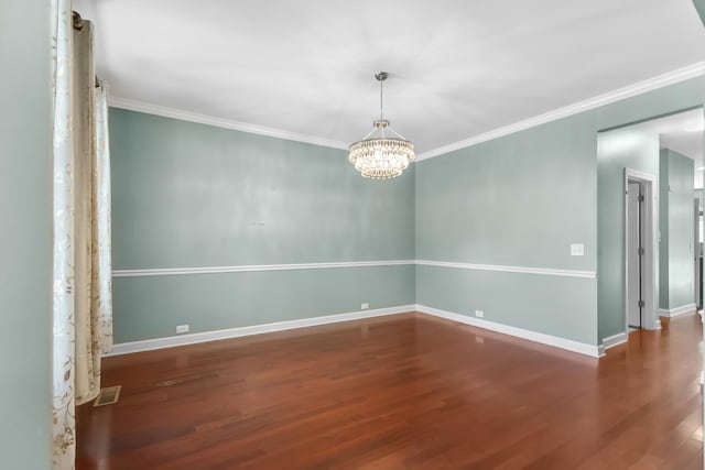 empty room featuring wood finished floors, ornamental molding, a chandelier, and baseboards