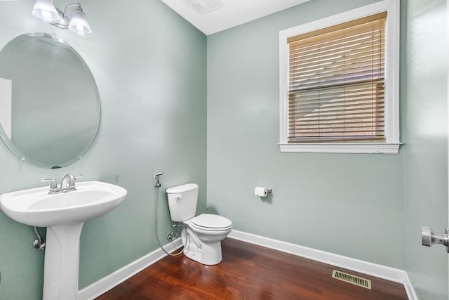 bathroom with baseboards, toilet, wood finished floors, and a sink