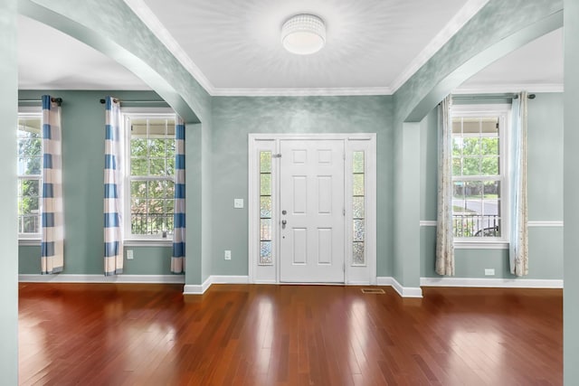 entrance foyer featuring arched walkways, hardwood / wood-style floors, baseboards, and ornamental molding