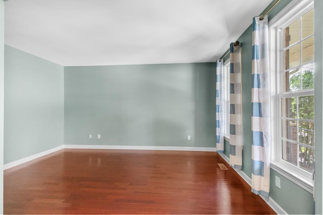 spare room featuring wood finished floors, plenty of natural light, and baseboards