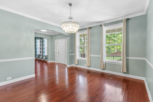 unfurnished dining area with arched walkways, baseboards, wood finished floors, a chandelier, and ornamental molding