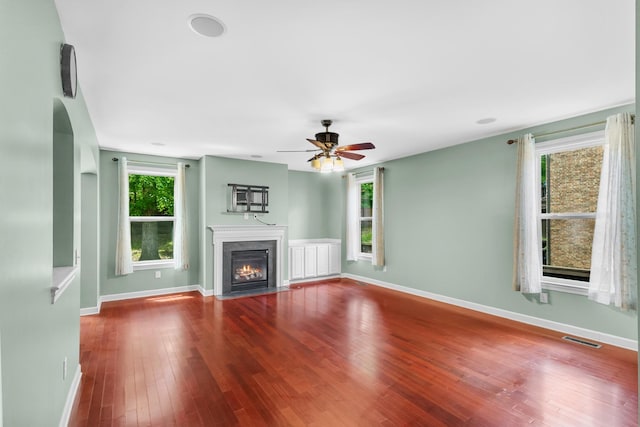 unfurnished living room with healthy amount of natural light, wood finished floors, and baseboards